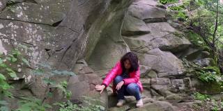 一个女孩在山上的一块岩石上进行地质勘探