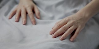 一个女人躺在床上，食指上拿着脉搏血氧计。手的特写镜头。医疗器械。血液中氧含量测定的概念