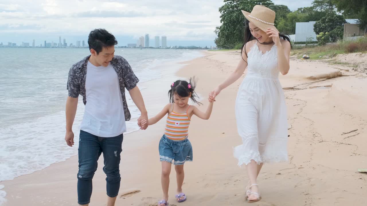 亚洲家庭与孩子在海滩散步快乐度假的概念