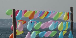 在伊斯坦布尔海岸，五颜六色的气球在风中一行行地摆动，背景是普林斯群岛之一