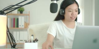 亚洲女学生或女商人远程工作和播客从家里与电脑笔记本电脑。保持社交距离的概念在covid-19.4k疫情下独自在家工作