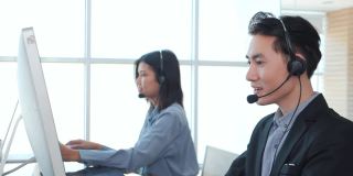 亚洲人戴着耳机与客户在办公室进行电话支持