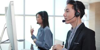 亚洲人戴着耳机在办公室与客户视频通话支持