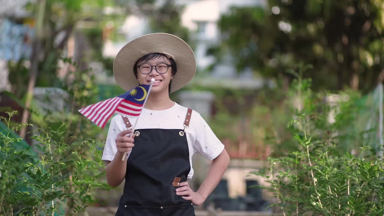 亚洲华人少年戴着口罩在自家农场挥舞国旗