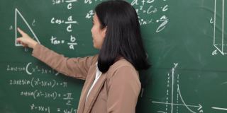 年轻的亚洲女教师与学生在摄像机视频会议上讲话。女教师在课堂上培训数学黑板在线课程。