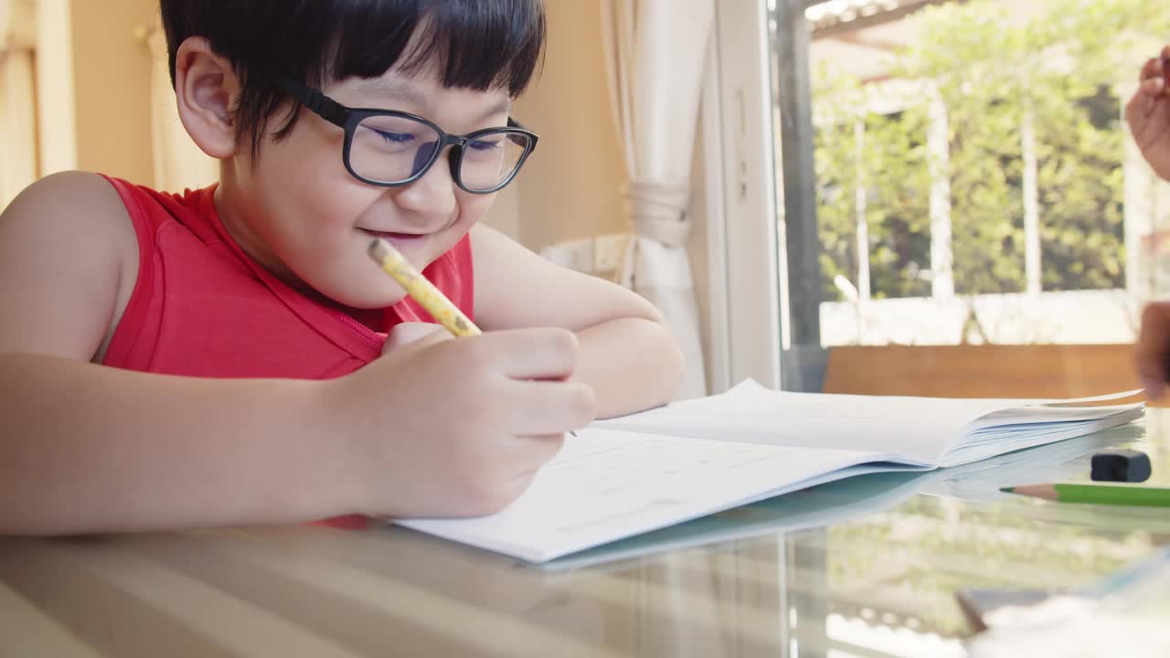 可爱伶俐的小男孩在家里坐在书桌前学习，学生在作业本上写作业，教育观念