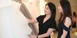 亚洲的中国女新娘和伴娘正在婚纱店为她的婚礼寻找完美的婚纱