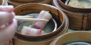 手用筷子吃传统的中国食物新鲜，美味，美味，美味的蒸肉点心在餐厅的竹篮