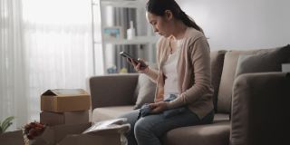 亚洲女人消费者觉得坐沙发不好，拿着电话与网店谈论家里订购的问题产品，打电话投诉。