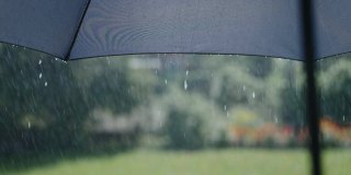 阳光明媚的夏雨。水珠从灰色的伞面上流下来