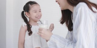 母女俩在家里的厨房里开心地喝着鲜奶。牛奶对孩子的身体发育有好处。家庭与爱生活在一起。周末活动快乐家庭生活理念