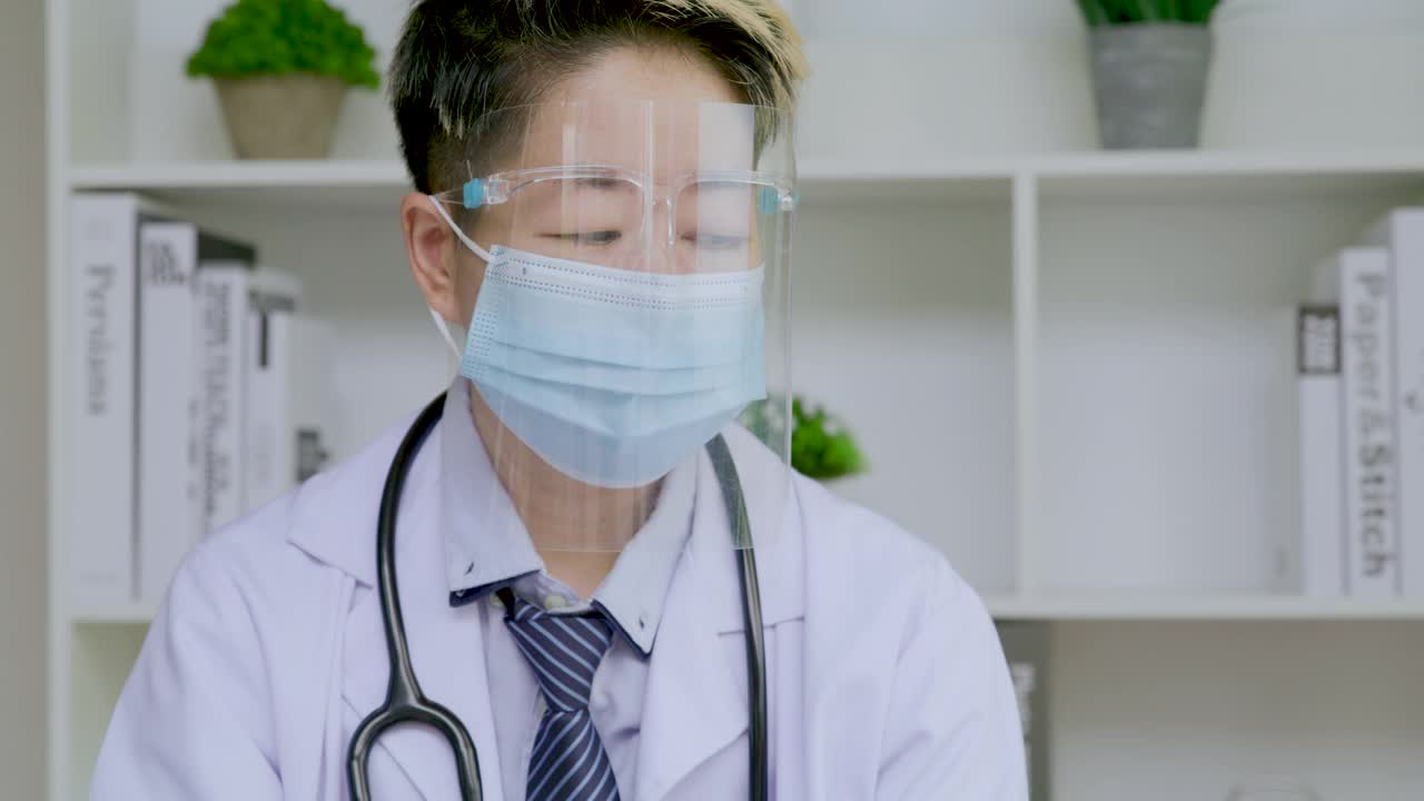 医生戴着面罩和口罩在诊所阅读文件和工作