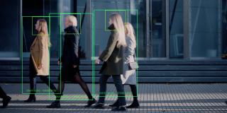 一群用科技跟踪的商人在繁忙的城市街道上行走。CCTV AI人脸识别大数据分析界面扫描，显示动画信息。