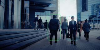 一群用科技跟踪的商人在繁忙的城市街道上行走。CCTV AI人脸识别大数据分析界面扫描，显示动画信息。