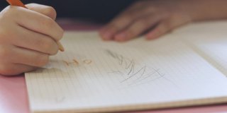 在阳光的照射下，孩子们在家里的书上写字和画画时，用铅笔对孩子们的手进行特写和选择性聚焦，显示出孩子们在学习教育方面的集中和专注的发展或训练。