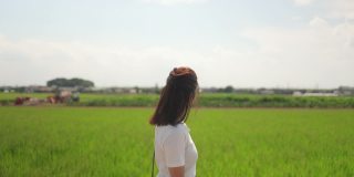 一名日本女子在夏天走在稻田里
