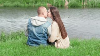 年轻夫妇坐在绿色的草地上。爱情故事，真爱。吻,拥抱。视频素材模板下载