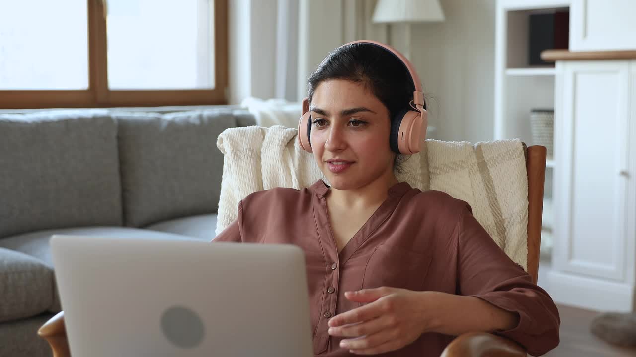 印度女性戴着耳机，用笔记本电脑进行视频会议