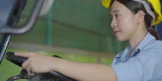 亚洲女工在工厂开叉车，看着镜头微笑
