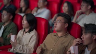 亚裔华人混合年龄段观众观看电影，在电影院排排坐欣赏电影视频素材模板下载