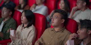 亚裔华人混合年龄段观众观看电影，在电影院排排坐欣赏电影