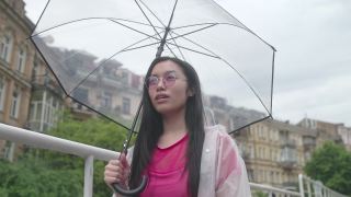 年轻的亚洲女人高兴雨停了，合上伞去散步视频素材模板下载