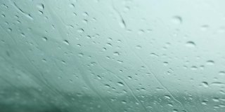 雨点沿着汽车的挡风玻璃落下。天气条件恶劣，秋天能见度有限。寒冷、潮湿、悲伤