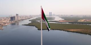 阿联酋国旗和Ras al Khaimah酋长国空中城市景观的标志性天际线上升在阿联酋北部的红树林和小溪