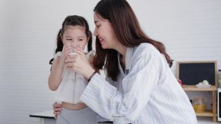 母女俩在家里的厨房里开心地喝着鲜奶。牛奶对孩子的身体发育有好处。家庭与爱生活在一起。周末活动快乐家庭生活理念视频素材模板下载