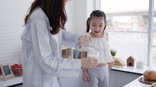 母女俩在家里的厨房里开心地喝着鲜奶。牛奶对孩子的身体发育有好处。家庭与爱生活在一起。周末活动快乐家庭生活理念视频素材模板下载