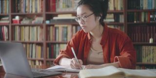 困倦疲倦的亚洲学生做笔记从在线课程，远程教育