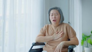 亚洲老年残疾妇女在轮椅上心脏病发作。老年女性胸痛，呼吸困难，紧抓胸部剧烈疼痛。医院保健和医疗理念。视频素材模板下载