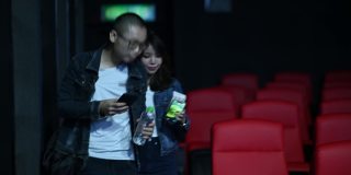 一对亚洲华人夫妇正在用手机app查询电影票的座位号