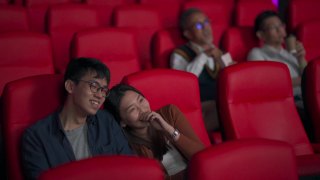 亚洲华人年轻夫妇喜欢在电影院看电影视频素材模板下载