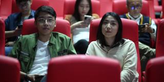亚洲的中国年轻夫妇在电影院等电影的时候，享受着彼此的陪伴