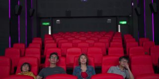 一个有两个孩子的亚洲华人家庭在电影院笑着看电影