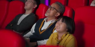 一位亚裔中国老人和他的孙女在电影院看电影睡着了