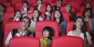 一位活跃的亚洲华人老人和他的孙女喜欢在电影院看电影