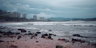 海滨的一个现代化的大海滨城市三亚，海南，摩天大楼。波浪在狂风暴雨的天气中翻滚，呈现出深沉的水色。阴沉的大海或海洋。