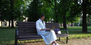 一个穿白衣服的黑发女人在公园里写笔记本