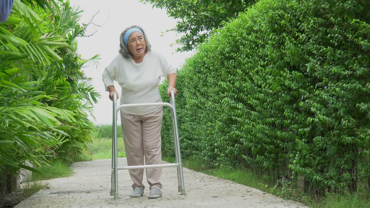 亚洲老年妇女忍受着在自家后院独自散步的痛苦