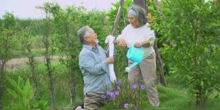 快乐的亚洲老夫妇在自家草坪上给植物浇水。老男人和老女人在后院共度时光。成熟的夫妻生活方式