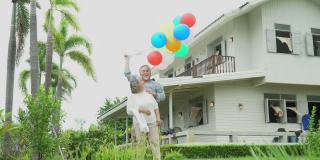 快乐的亚洲老夫妇拿着气球在家门口的草坪上。老男人和老女人在后院共度时光。一对成熟的夫妻在花园里庆祝结婚纪念日。