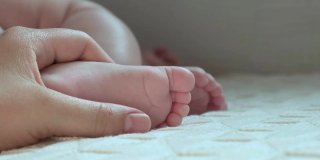 妈妈手里抱着宝宝的脚。新生儿在女性父母手中。小孩子的脚在妈妈的手掌里。特写镜头。孩子的小脚趾和快乐父母的女人的手。母亲节的节日。