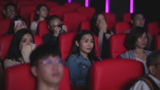 亚洲的中国人群在电影院看恐怖的惊悚电影视频素材模板下载
