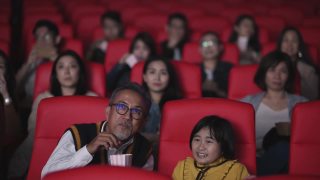 亚洲华人活跃的老人和他的孙女在电影院看恐怖惊悚电影视频素材模板下载