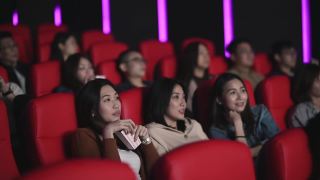 亚洲的中国女人在电影院看恐怖的惊悚电影，和其他观众一起看视频素材模板下载