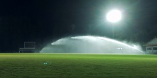 用智能手机慢动作拍摄夜间足球场上的洒水装置