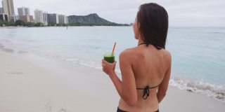 蔬菜绿色排毒净化冰沙-女人在夏天游泳锻炼后喝。女孩喝绿色果汁或冰沙健身和健康的生活理念。海滩上美丽的模特。