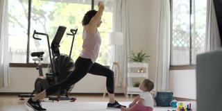 健康的妈妈在家锻炼，而她的宝宝在玩耍